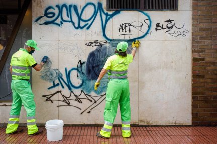 Trabajadores de limpieza eliminan grafitis sobre una pared.
