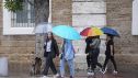 Varias personas pasean bajo la lluvia.