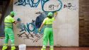 Trabajadores de limpieza eliminan grafitis sobre una pared.