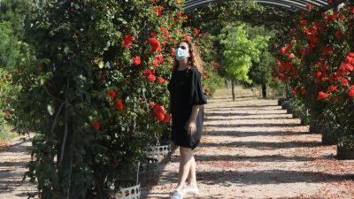 Una mujer pasea con mascarilla por un jardín botánico.