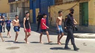 Un agente de la policía nacional junto a varios de los inmigrantes que han llegado a nado este lunes a Ceuta (Efe).
