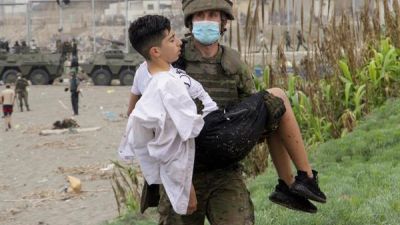 Un soldado del Ejército de Tierra ayuda a un inmigrante que ha logrado cruzar uno de los espigones fronterizos de Ceuta.