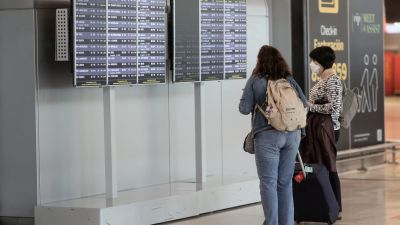 Dos pasajeras miran horarios de vuelo en un aeropuerto.