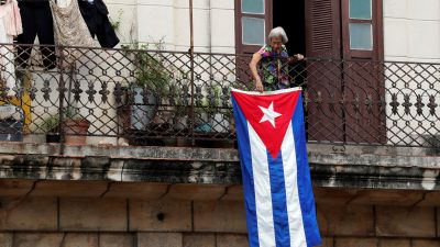 Una mujer coloca la bandera cubana en su balcón.