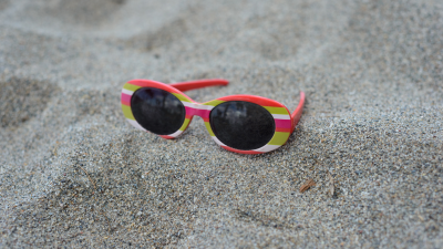 Fotografía de unas gafas de sol de niño en la playa (Canva).