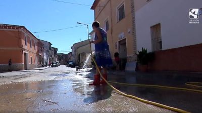 Una vecina de Sena limpia la calle con una manguera.