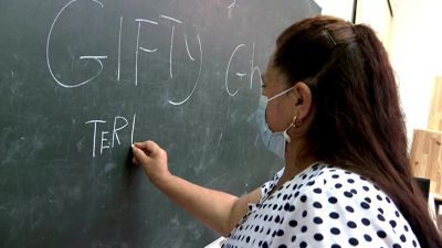 Una mujer aprende a escribir su nombre en una pizarra.