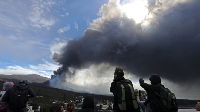 Varios turistas contemplan la erupción volcánica desde la plaza de Tajuya. (Foto: EFE)
