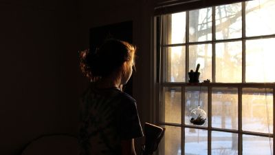 Una niña mira por la ventana.