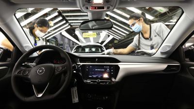 Vista del interior de un coche mientras dos personas desarrollan su trabajo en la planta de Figueruelas. / Foto: EP
