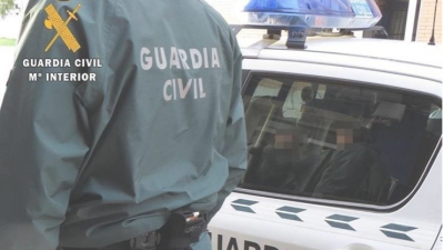 Un agente de Guardia Civil junto a un coche patrulla.
