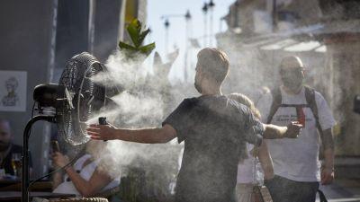 Un chico se refresca con un difusor de vapor de agua de un restaurante.
