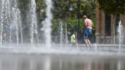 Un hombre y un niño se refrescan en una fuente. / Europa Press