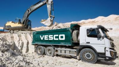 Una máquina retroexcavadora y un camión, en una cantera. / Vesco