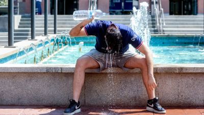 Un joven se tira una botella de agua por encima para combatir la segunda ola de calor del verano. / Europa Press