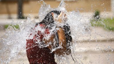 Una joven se refresca en una fuente. / EFE.