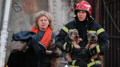 Un rescatista ucraniano ayuda este lunes a una mujer herida y a sus perros tras un bombardeo en el centro de Kiev (Ucrania). (EFE/ Sergey Dolzhenko).
