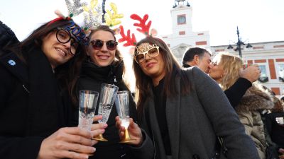 Varias personas brindan con cava tras comerse las famosas "preúvas" este sábado al mediodía en la Puerta del Sol de Madrid. / EFE.