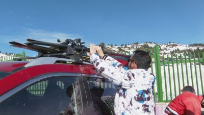 Un conductor coloca los esquís en la baca del coche.