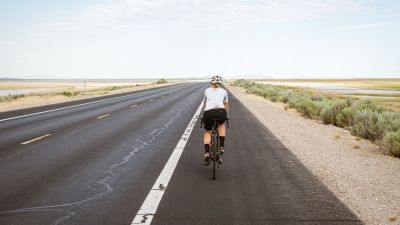 Una ciclista circulando por una carretera con arcén.