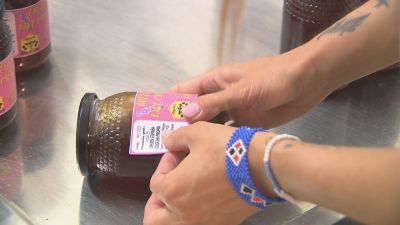 Una persona colocando una etiqueta a un bote de miel.