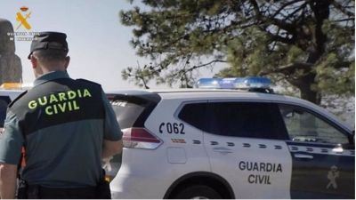 Un agente de la Guardia Civil junto a un coche oficial. / Guardia Civil.