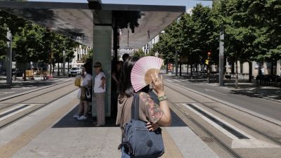 Una mujer se tapa del sol con un abanico en la parada del tranvía del Paseo de la Independencia de Zaragoza. / Europa Press