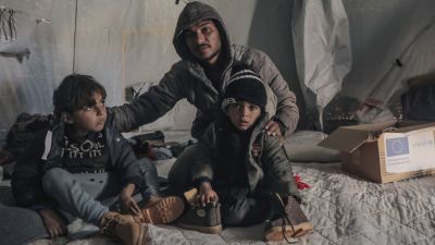 Un hombre y dos niños palestinos en el campamento de Al Zapin, en Deir al Balá, en la Franja de Gaza./ Mohamed Nateel / UNICEF