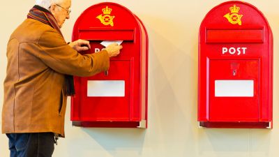 Un hombre echando una carta en un buzón. / Canva