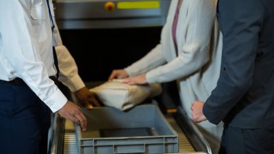 Una pasajera recoge sus pertenencias de la bandeja tras pasar un control en un aeropuerto. 