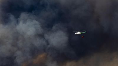 Un helicóptero trabaja en las labores de extinción del incendio forestal en Niebla (Huelva) este sábado, en el que participan veinte medios aéreos, 275 efectivos y 94 vehículos.