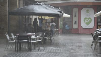 (Foto de ARCHIVO)Varias personas se protegen de la lluvia en una terraza de Huesca.